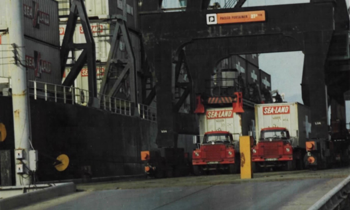 Two lorries take Sea-Land containers directly off a ship at Cam Ranh Bay, with the gantry crane overhead.